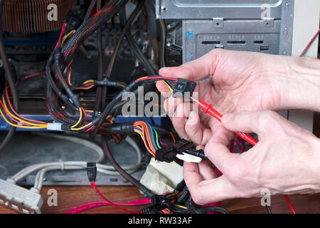 L uomo è il test di potenza elettrica di personal computer. Computer di processo di riparazione. Il tecnico di riparazione di apparecchiature Foto Stock