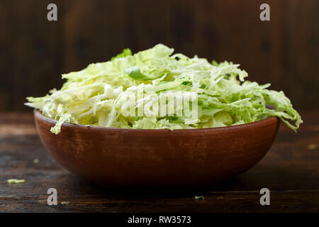 Tritate finemente la verza in una piastra su un sfondo di legno. spazio per il testo Foto Stock