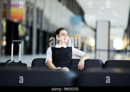 Ritratto di sorridente giovane imprenditrice in attesa in aeroporto, lobby spazio copia Foto Stock