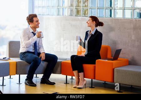 Due colleghi a chattare su pausa caffè in un moderno centro business. Foto Stock