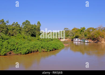 Densamente boscoso rive del fiume Aquidauana in brasiliano Pantanal, houseboats sul greto del fiume, Brasile Foto Stock