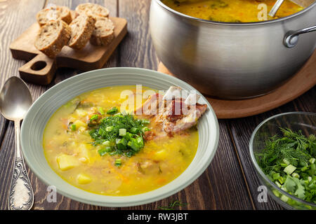 Giallo fragrante dividere la zuppa di piselli con carne di maiale affumicato nervature su un tavolo di legno. Foto Stock