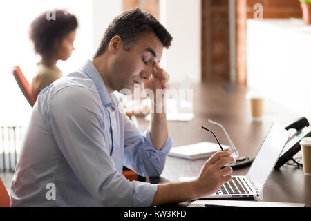 Stanco ha sottolineato di mezza età imprenditore tenendo bicchieri sento affaticamento degli occhi durante il lavoro Foto Stock