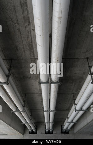 White liquami industriali e tubi di acqua al di sotto di un ponte di cemento in Svizzera Foto Stock