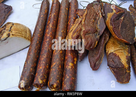 In casa salsicce affumicate ed essiccato e altri prodotti stand sul tavolo per la vendita. Foto Stock