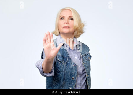 Grave senior european donna in piedi con la mano tesa che mostra il gesto di arresto isolate su sfondo bianco Foto Stock