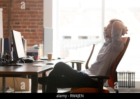 Giovane imprenditore tenendo pausa di lavoro rilassante in sedia ergonomica Foto Stock