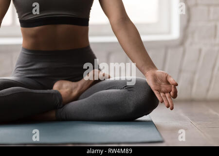 Giovane donna a praticare yoga, seduto in Padmasana pongono, Lotus esercizio Foto Stock
