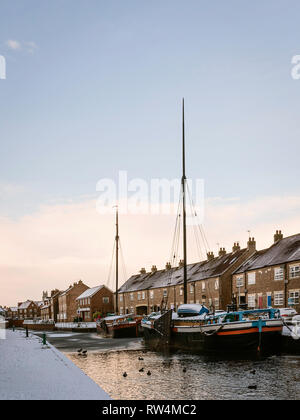 Vintage chiatte ormeggiate lungo la congelati beck (canale) e coperta di neve fiancheggiate da case in Beverley, Yorkshire, Regno Unito. Foto Stock