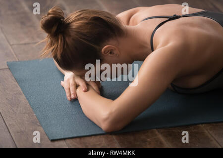 Giovane donna a praticare yoga, sdraiato a faccia in giù, rilassante dopo il corso di formazione Foto Stock