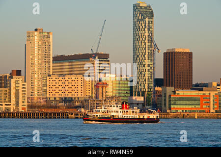 Il Traghetto Mersey vele di fronte a Liverpool, famoso in tutto il mondo gli edifici sul lungomare illuminato dalla tarda sera sun. Foto Stock