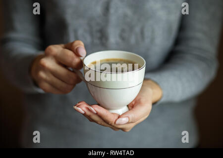 Una tazza di delizioso caffè in mani femminili. Concetto di bevande, stile di vita, lavoro, sfondo Foto Stock