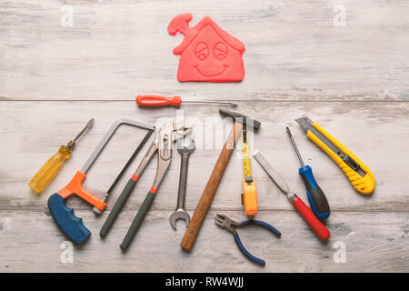 Gruppo di utensile di lavoro su rustiche in legno con sfondo icona della casa in spazio, industria strumento tecnico di concetto.still-life. Foto Stock