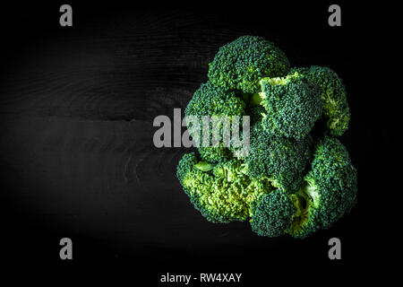 Brokkoli isolate su legno scuro board su sfondo nero Foto Stock