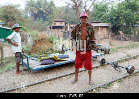 Gli uomini posizionando la piattaforma di bambù sulle ruote, il treno di bambù; Battambang, Cambogia Foto Stock
