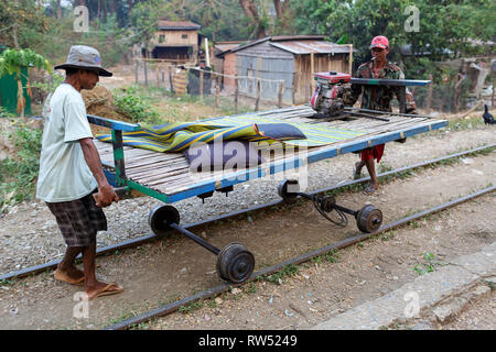 Gli uomini posizionando la piattaforma di bambù sulle ruote, il treno di bambù; Battambang, Cambogia Foto Stock