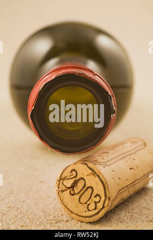 Close-up di un tappo di sughero e bottiglia di vino su una trama beige sfondo della carta Foto Stock