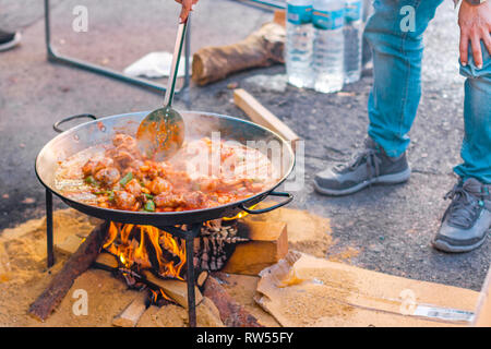 La paella preparazione su strada durante il Fallas festività. Valenciana paella di pollo. Foto Stock