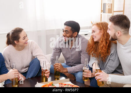 Amici avente una piccola parte, mangiare la pizza a casa Foto Stock