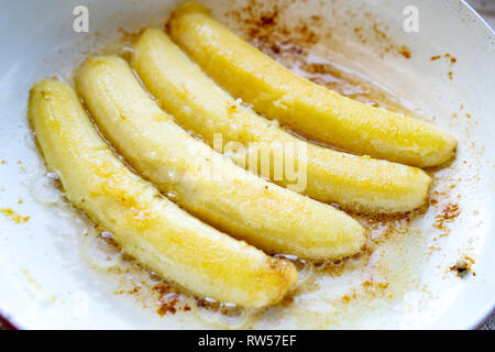 Banane fritte in una padella di bianco durante la cottura Foto Stock