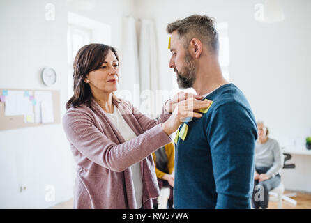 Consigliere mettendo un adesivo note sul client durante una terapia di gruppo. Foto Stock