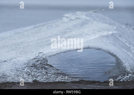 Incrinature di ghiaccio e fusione sul lago ghiacciato e fare un foro di ghiaccio. Foto Stock