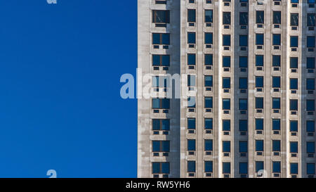 Modello regolare fatta di finestre rettangolari sul blocco di appartamenti / edificio uffici. Cielo chiaro (luogo di testo) sul lato sinistro. Foto Stock