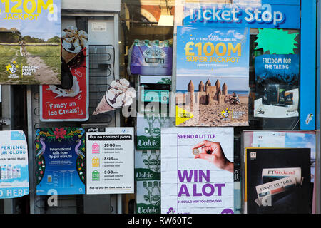 Biglietti della lotteria e annunci pubblicitari di ricarica per telefono cellulare pubblicati incollati sulla vetrina di un negozio di edicole a Londra Inghilterra Regno Unito KATHY DEWITT Foto Stock