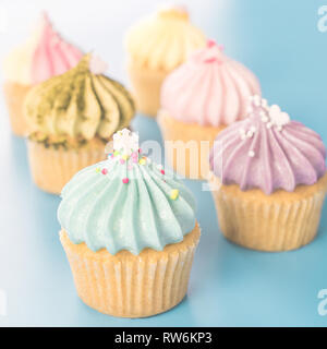 Mini Tortine di fantasia muffin luminoso su sfondo blu Foto Stock