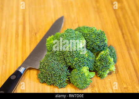 Fresche, materie broccoli su un legno tagliere con un coltello chef Foto Stock