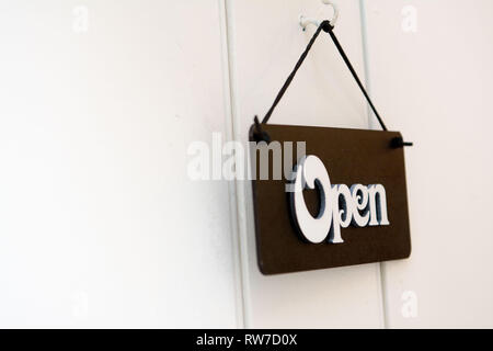 Bianco porta in legno bianco con segnaletica aperta su sfondo nero Foto Stock