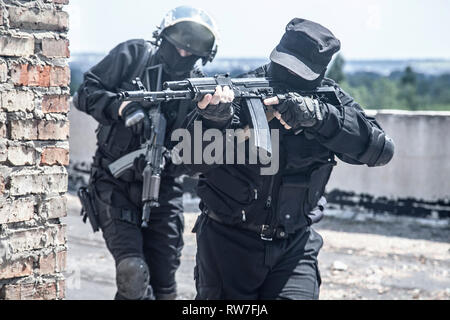 Due spec ops soldati in uniforme nera in azione. Foto Stock