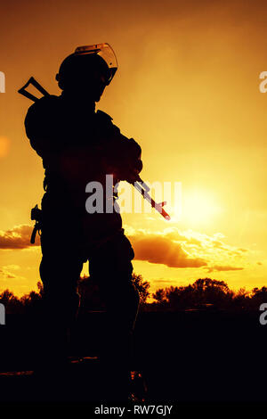 Silhouette di un funzionario di polizia con armi al tramonto. Foto Stock