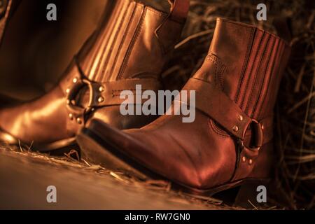 Western in cuoio aspetto stivali da cowboy nel granaio Closeup Photo. Foto Stock