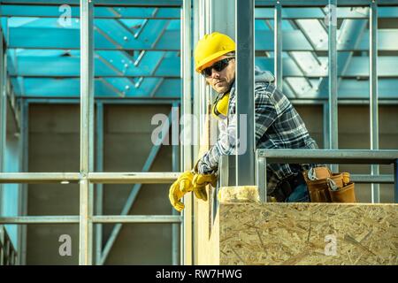 Costruzione professionale Lavoratore e lo scheletro del telaio in acciaio dell'edificio sviluppato. Lavoratore caucasica nel suo 30s. Foto Stock