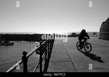 Un ciclista sul lungomare bandstand lo sviluppo a Ventnor Harbour, Ventnor, Isle of Wight, Inghilterra, Regno Unito. Foto Stock