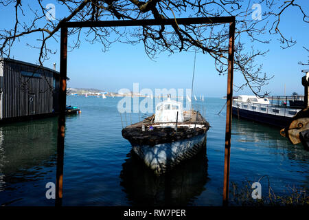 Un motore torpediniera giace a terra in corrispondenza di ormeggio nel porto di Bembridge, Bembridge, Isola di Wight. È incorniciata da una vecchia struttura di tubazione in primo piano. Foto Stock