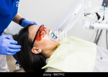 Laser denti sbiancante a dantist camera. Lo sbiancamento dei denti per donna. Sbiancamento dei denti al dentista clinica. Foto Stock