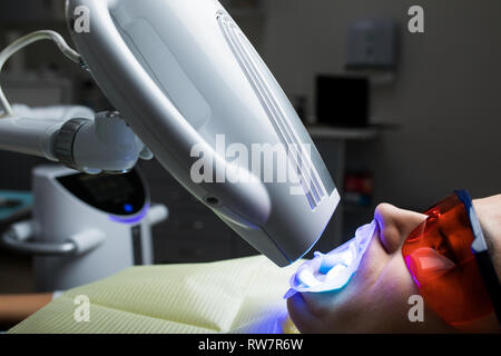 Femmina adulta la ricezione di sbiancamento dei denti procedura.ritratto di un paziente di sesso femminile al dentista in clinica. Lo sbiancamento dei denti procedura con ultravioletti lig Foto Stock