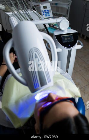 Femmina adulta la ricezione di sbiancamento dei denti procedura.ritratto di un paziente di sesso femminile al dentista in clinica. Lo sbiancamento dei denti procedura con ultravioletti lig Foto Stock