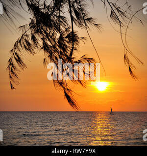 Fotografia quadrata con la silhouette di una barca a vela all'orizzonte durante il tramonto visto da di Otres Spiaggia, a Sihanoukville, Cambogia, in Asia. Foto Stock