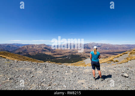 Mt Cheeseman, Canterbury, Nuova Zelanda, 2 Marzo 2019: una donna arriva sulla cima del mountain bike via a prendere in una vista fantastica sulla vallata Foto Stock