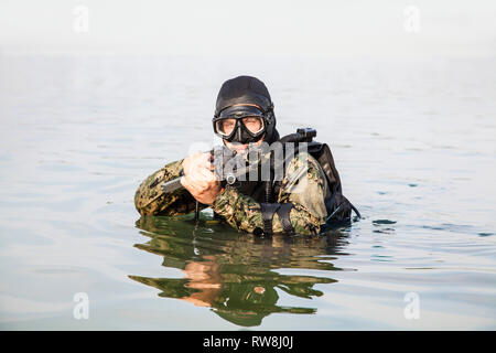 Navy Frogman tenuta con attrezzatura completa e armi nell'acqua. Foto Stock