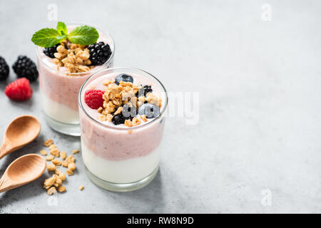 Berry yogurt con frutti di bosco freschi e granola in barattolo. Yogurt Greco, sana colazione parfait in coppa di vetro. Copia spazio per il testo Foto Stock