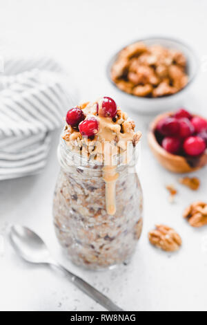 Per una notte di avena con frutti di bosco e il dado burro in vaso. Una sana prima colazione. Vegano vegetariano e perdita di peso la dieta concetto Foto Stock