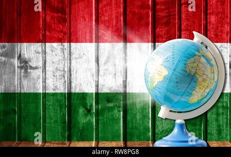 Globo con una mappa del mondo su un sfondo di legno con l'immagine della bandiera dell'Ungheria. Il concetto di viaggio e il tempo libero all'estero. Foto Stock