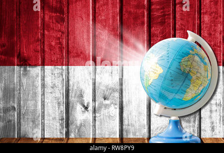 Globo con una mappa del mondo su un sfondo di legno con l'immagine della bandiera dell'Indonesia. Il concetto di viaggio e il tempo libero all'estero. Foto Stock