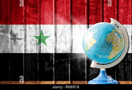 Globo con una mappa del mondo su un sfondo di legno con l'immagine della bandiera della Siria. Il concetto di viaggio e il tempo libero all'estero. Foto Stock