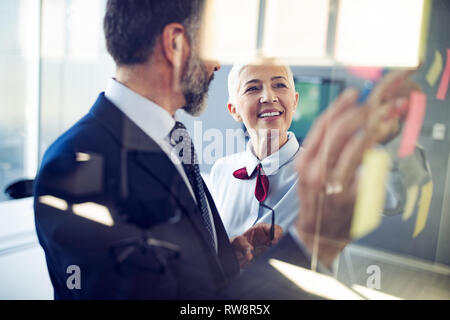 Lavoro di squadra creativa nella parte anteriore della parete di vetro utilizzando post-it e adesivi Foto Stock