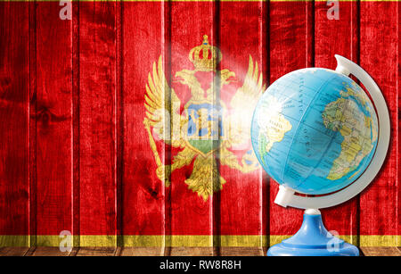 Globo con una mappa del mondo su un sfondo di legno con l'immagine della bandiera del Montenegro. Il concetto di viaggio e il tempo libero all'estero. Foto Stock